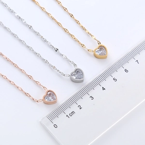 Three stainless steel heart necklaces in rose gold, silver, and gold with scale ruler