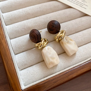 Détail de boucles d'oreilles vintage avec clous en bois, boucles dorées et pendentifs en résine
