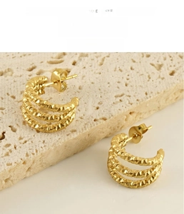 Macro shot of three-layered golden U-shape earrings with hammered texture details