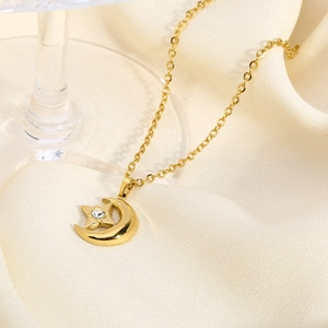 Close-up of star and moon gold pendant necklace with crystal on champagne silk background