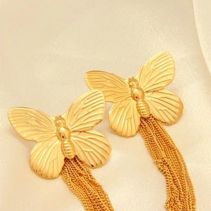 Macro detail of gold butterfly earrings featuring elegant metal chain tassels and high gloss