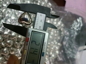 Close-up of heart-shaped silver CCB bead measurement showing 2.14mm thickness with caliper