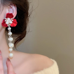 Detail of elegant red flower earrings with long hanging white pearls and crystals