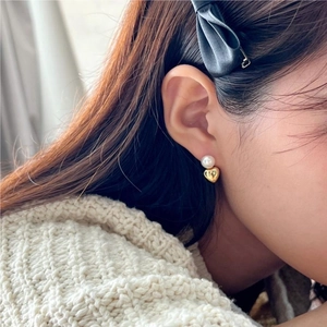 Close-up of elegant 925 silver earring with white pearl and gold heart pendant on model