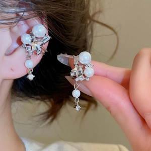 Detail of star-shaped zircon and pearl ear cuff set with dangling sparkling accents