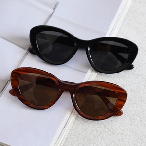 Flat lay of vintage cat eye sunglasses in black and tortoiseshell on a white marble base