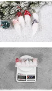 Detail view of 5 knit Christmas gnomes with striped hats and weight measurement on scale
