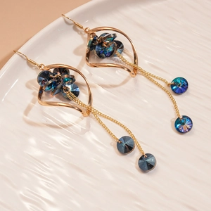Detailed shot of twisted gold metal earrings with navy blue crystal tassels on a plate