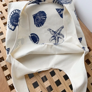 Detailed texture of off-white canvas tote bag featuring blue seashell and starfish prints