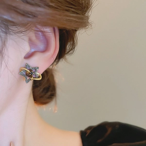 Detailed close-up of a vintage golden star planet earring worn on a model ear lobe