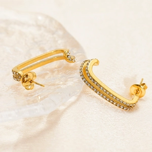 Golden rectangular C-shape double-layer earrings with sparkling crystals on glass tray