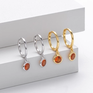 Detailed view of silver and gold round gemstone earrings with orange cubic zirconia stones