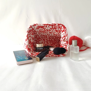 Detail of handmade crochet cloud bag with red and white stitching and metal buckle