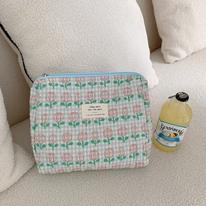 Quilted floral makeup bag with tulip pattern and blue zipper on a white plush surface