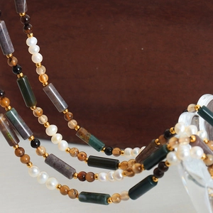 Handmade necklace with freshwater pearls, natural stones, and golden beads on dark wood