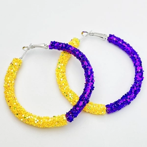 Macro detail of yellow and purple glitter sequins on large round hoop earrings