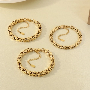 Detailed view of three gold Byzantine weave stainless steel bracelets on beige background