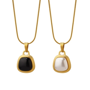Elegant gold snake chain necklace featuring black and white shell pendant charms
