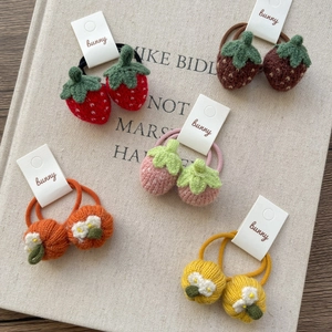 Handmade knitted strawberry and pumpkin hair ties for girls on a wooden background