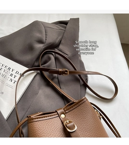 Close-up of brown lychee texture leather bucket bag with adjustable strap and metal buckle