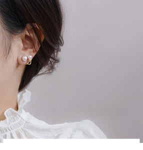 Detailed close-up of an elegant pearl stud earring with a golden ring on a model's ear