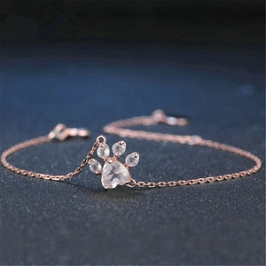 Close-up of rose gold bracelet with cat paw pendant and heart-shaped gemstone