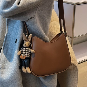 Chic brown leather crescent shoulder bag for women with cute woven rabbit charm