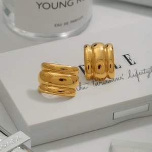 Macro detail of gold triple-layered wide hoop earrings with a mirror polished finish