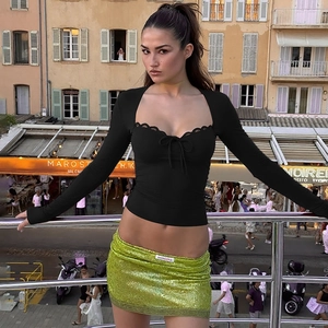Détail du haut noir à manches longues avec dentelle et mini-jupe à paillettes vertes