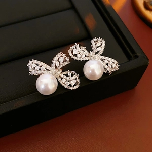 Détail de boucles d'oreilles perles avec nœud en zircon sur un présentoir à bijoux noir