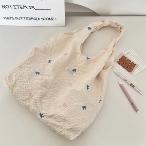 Détail de nœuds brodés colorés sur un sac fourre-tout beige en toile à texture gaufrée