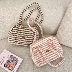 Détail de sacs à main en peluche rayée avec plaque logo en métal et texture douce