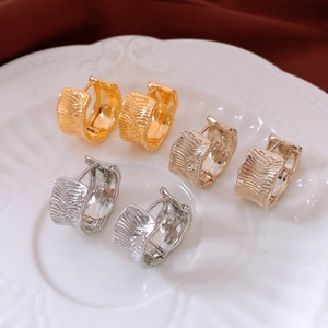Detailed view of three pairs of textured 18K gold plated wrinkled hoop earrings on a plate