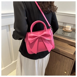 Vista posteriore di una modella con la borsa a tracolla rosa shocking e fiocco grande
