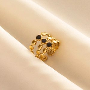 Three-layer hollow golden stainless steel ring with black enamel dots on silk fabric
