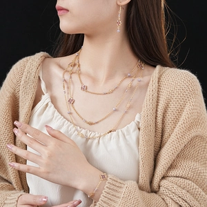 Detail of vintage gold jewelry set with pink clover motifs and lilac beads on model