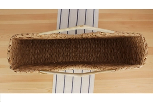 Top view of natural straw beach bag with gold thread weaving and wooden handles