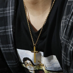 Detail of a men's gold cross pendant necklace paired with a 3mm twisted rope chain