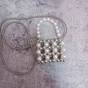 Detail of silver metallic and pearl woven beads on mini bag with long metal chain