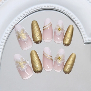 Press-on nails with 3D white flowers, gold foil accents and glitter in long oval shape