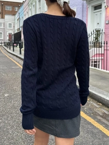Detail of navy blue cable knit sweater featuring thick textured weave and rear view on model