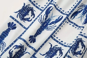 Detailed view of white fabric featuring blue lobster and crab print in ink-wash style