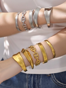 Brazaletes anchos irregulares y cadenas de eslabones H en oro y plata sobre una modelo