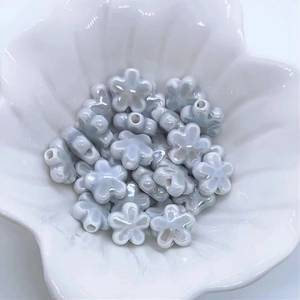 Dettaglio macro di perle di fiori di prugno in ceramica azzurra per gioielli fai-da-te