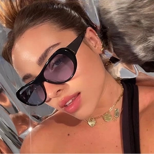 Oval black frame sunglasses with purple gradient lenses and gold chain jewelry on model