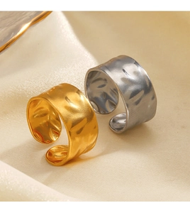 Macro detail of irregular hammered gold and silver wide bands on beige silk fabric