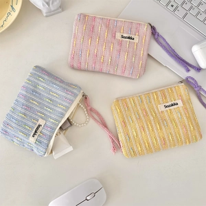 Close-up of three colorful woven fabric makeup bags with textured stripes and zippers