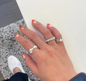 Close-up of minimalist sterling silver star rings set worn on hand in a modern casual style