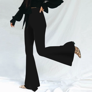 Dynamic view of high-waisted black flared trousers with wide leg cut on white background