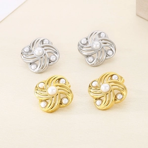 Detailed view of gold and silver spiral flower earrings set with elegant white pearls